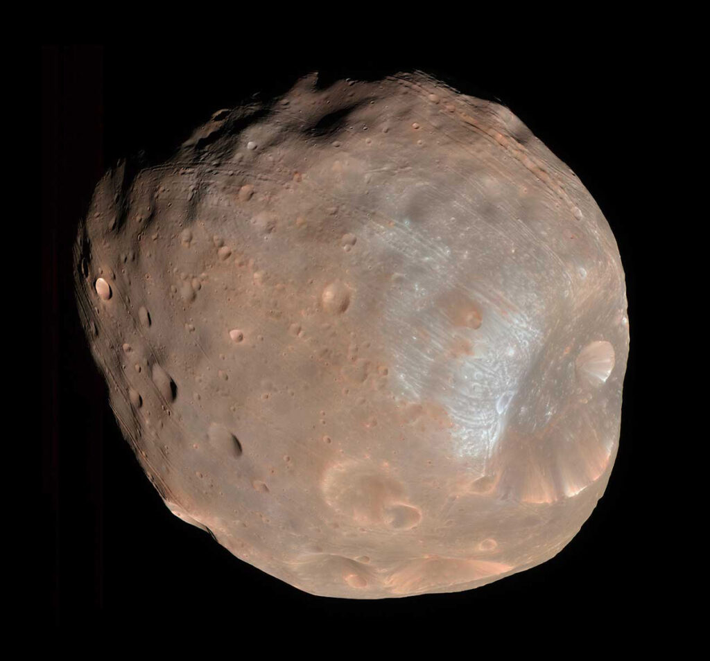 A battered-looking, reddish-orange moon of Mars floats against a dark background.