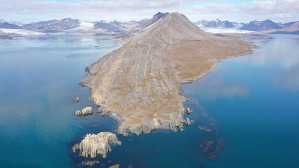 A drone image of a piece of mountainous land jutting out into the blue ocean.