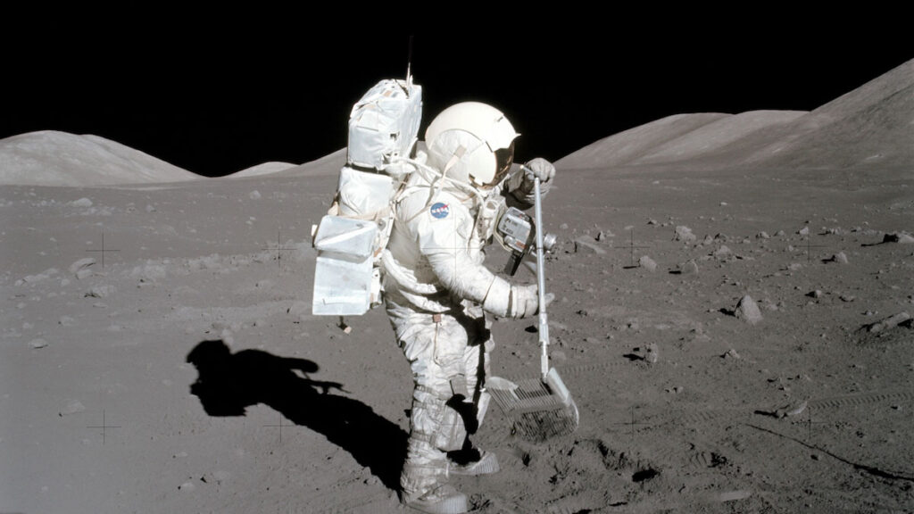 An astronaut on the Moon collects a lunar sample with a rake.
