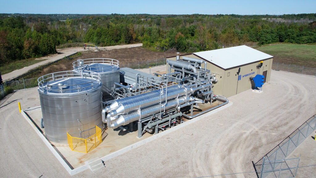 A building connected to a series of large shiny metal tubes and two metal towers is seen from above.