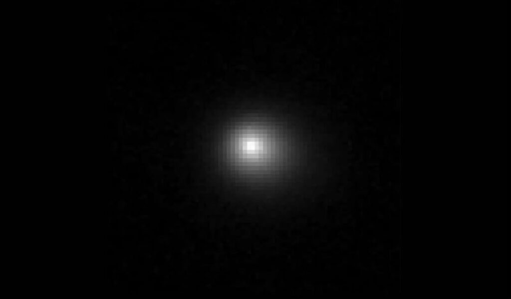 A slightly pixelated image of a comet with a short tail. The comet is white on a black background.