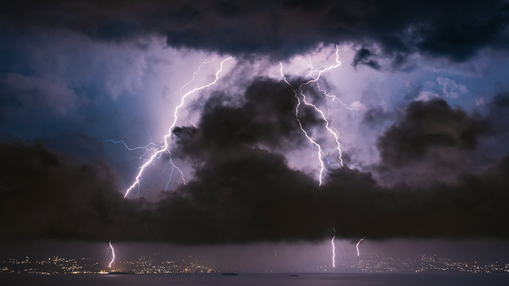 Photo of lightning bolds behind clouds at night.