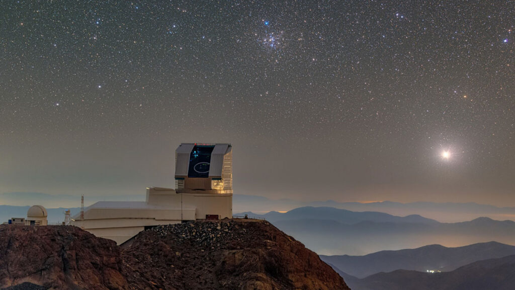 A large observatory on a mountaintop with a starry sky in the background.