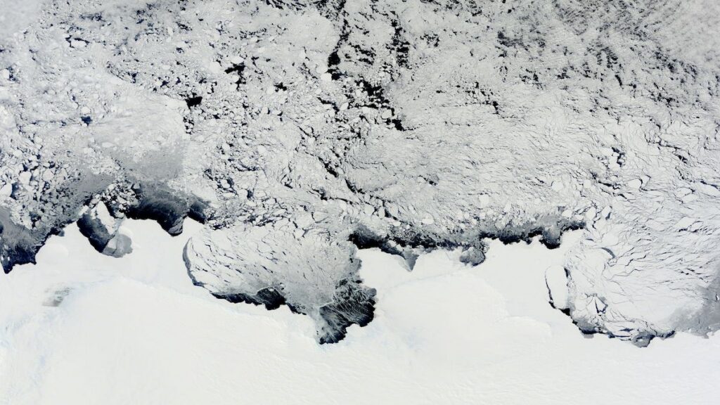 A satellite image shows the edge of an Antarctic ice sheet meeting a frozen ocean.