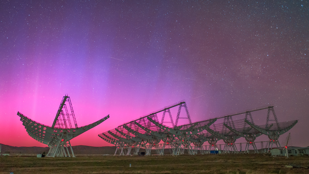 Photo of a telescope under an aurora.