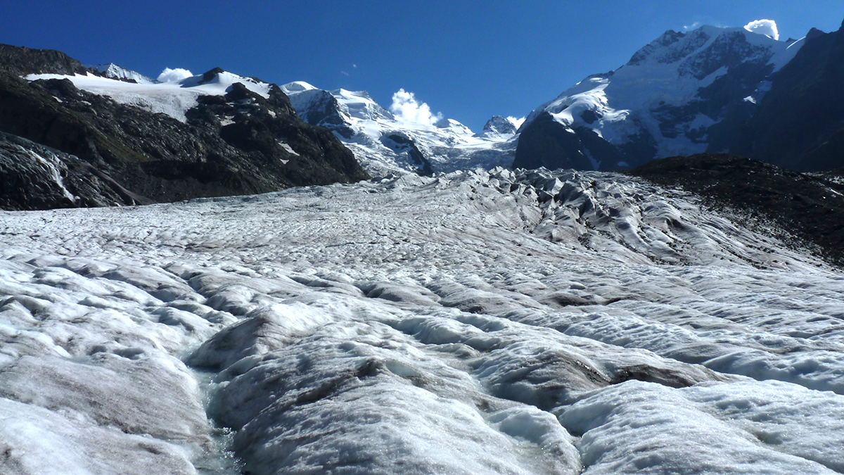 Photo of a glacier with mountains in the background.