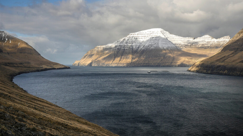 A large fjord with rocky, snow-covered mountains in the background