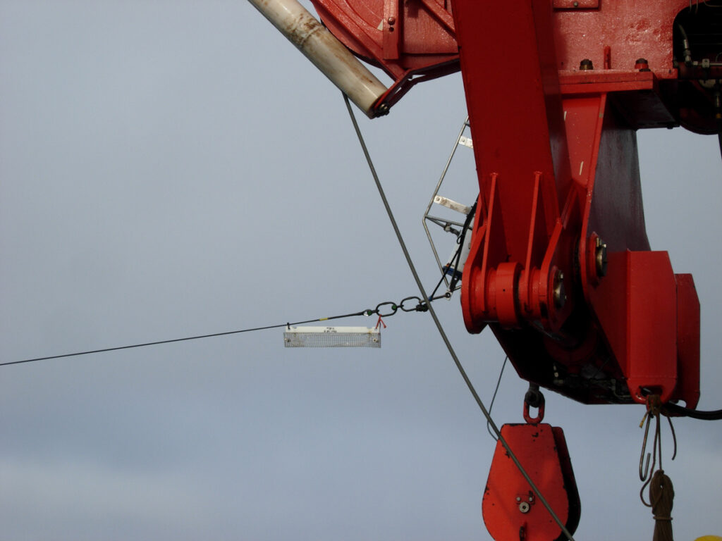 A pulley system mounted on a red beam pulls a small envelope filled with water along a string.