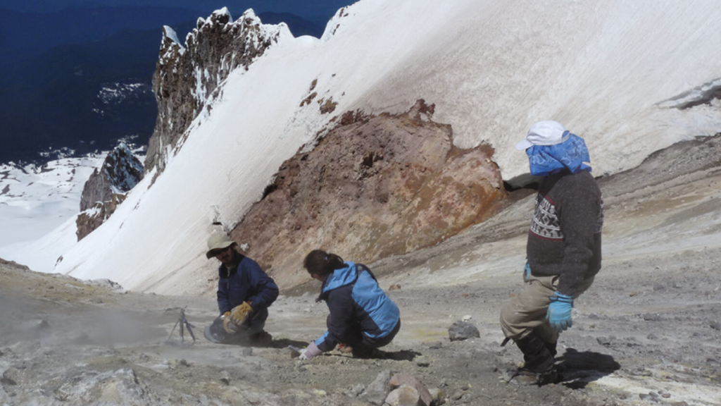Three scientists working on the side of a mountain.