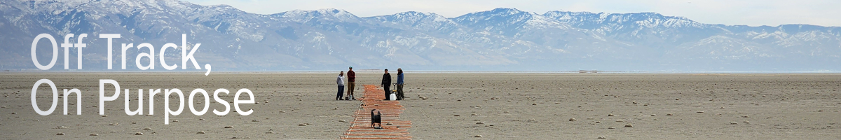 Researchers stand in the distance as an orange electrical cord snakes across a dry lake bed in the Great Salt Lake.