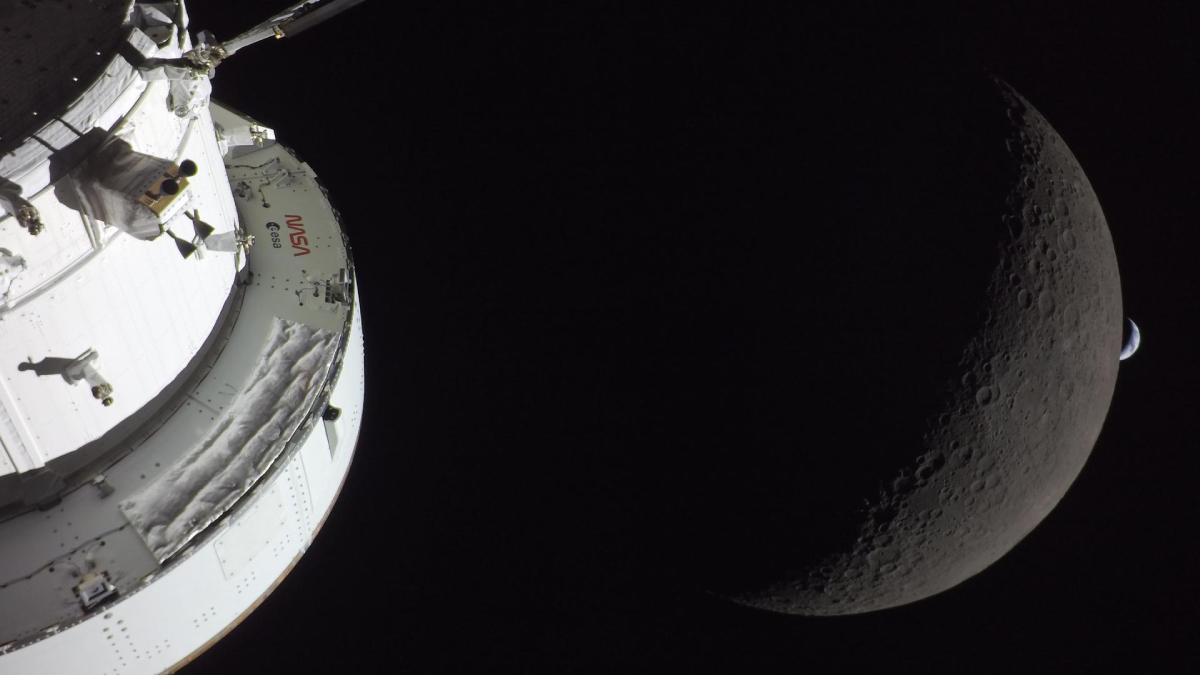 A photo of the Orion spacecraft in front of a crescent of the farside of the Moon, which is in front of a crescent of the Earth in the distance