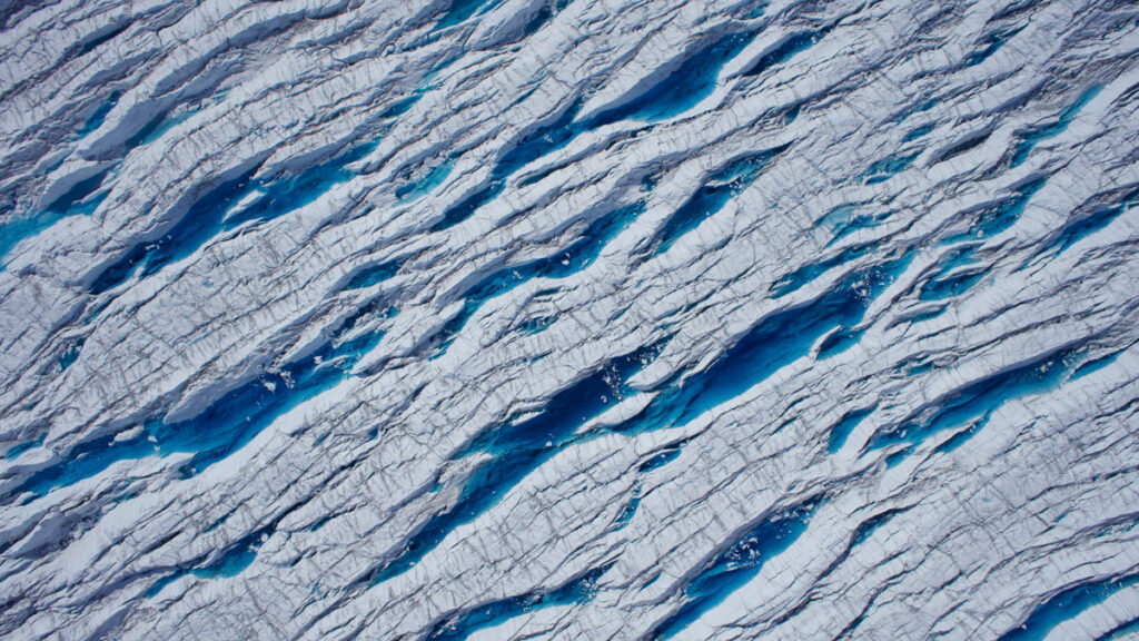 Crevasses on a glacier are seen from overhead.