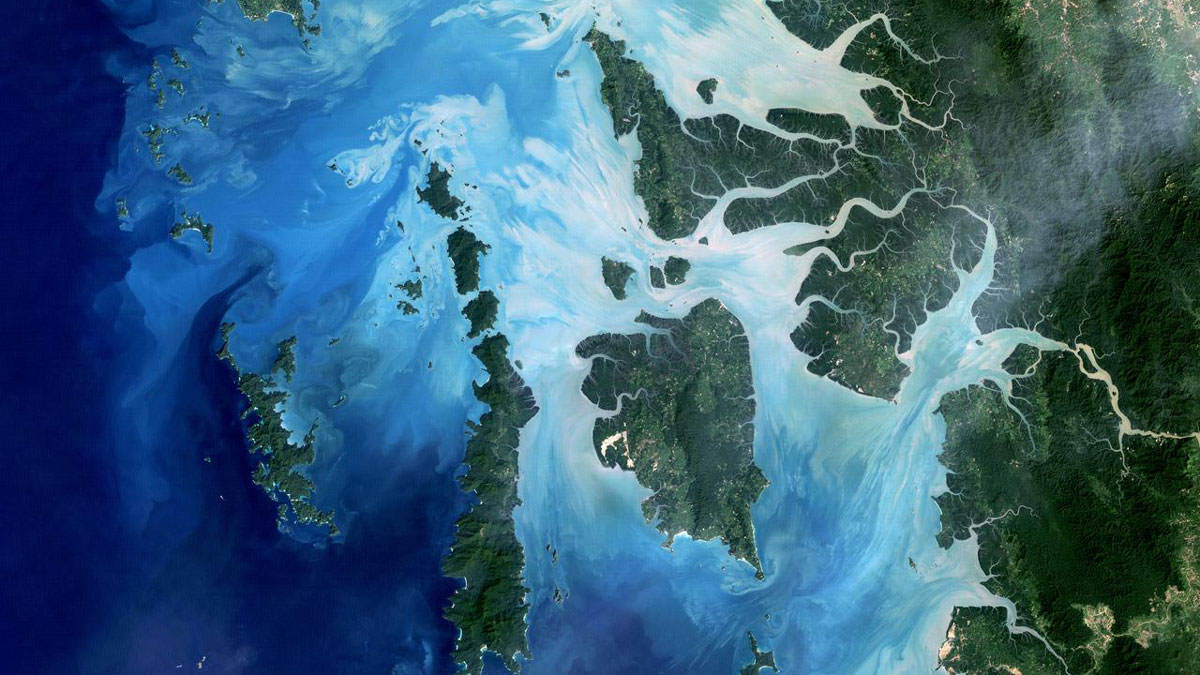 Satellite image of the Mergui Archipelago off Myanmar, showing swirls of organic matter and sediment flowing into the ocean near coastal coral reefs.