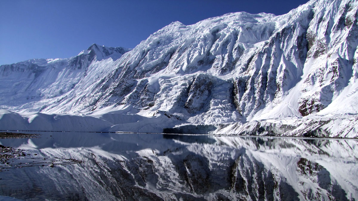 A snowy mountain is reflected on a lake.