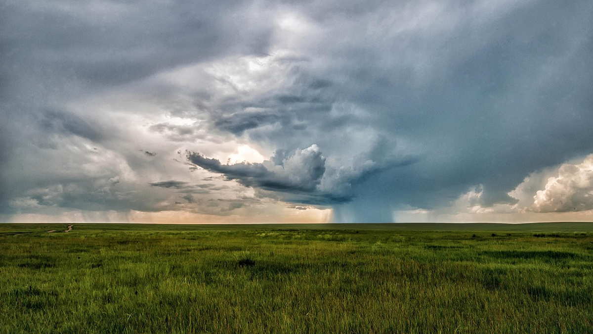 Photo of a stormy sky over a field of grass.