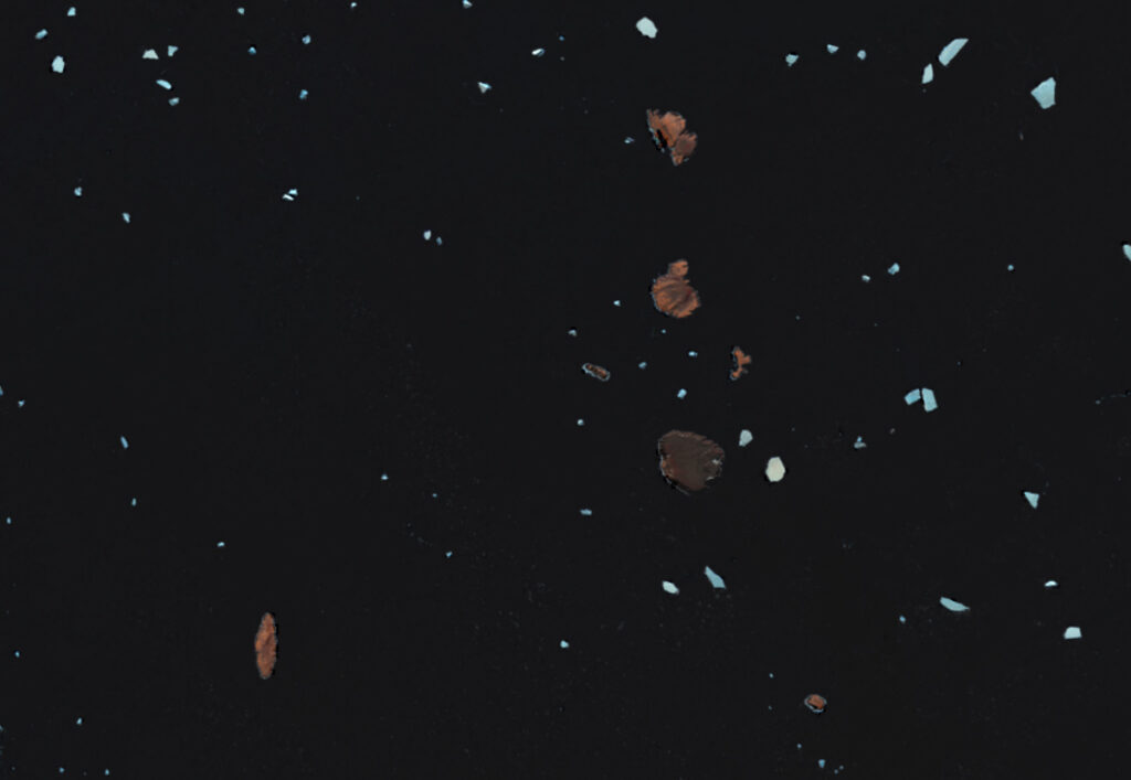 A satellite image shows a collection of islands and sea ice. The sea ice is colored white, and the islands are colored reddish pink.