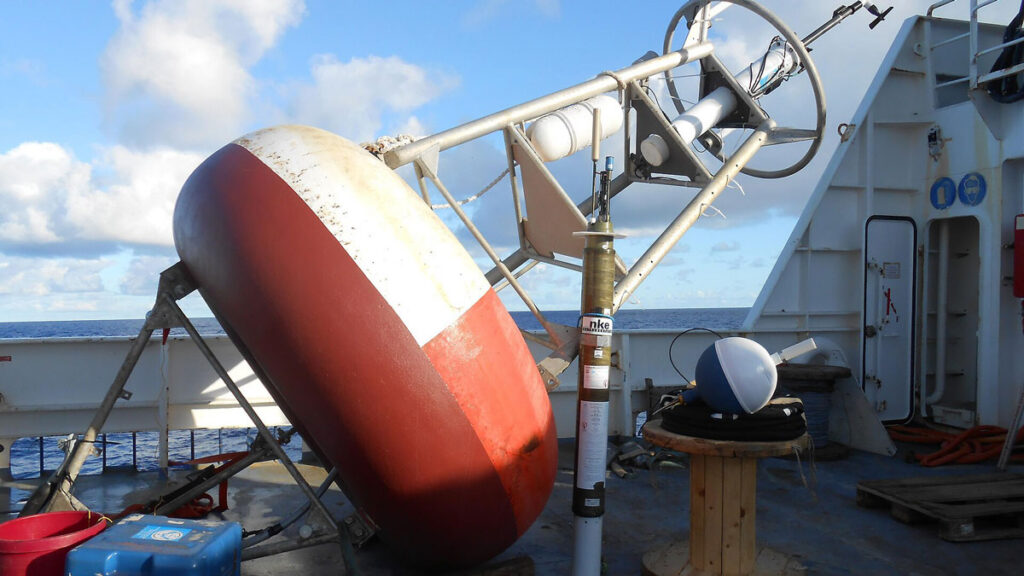 A large red buoy sits on the deck of a ship.