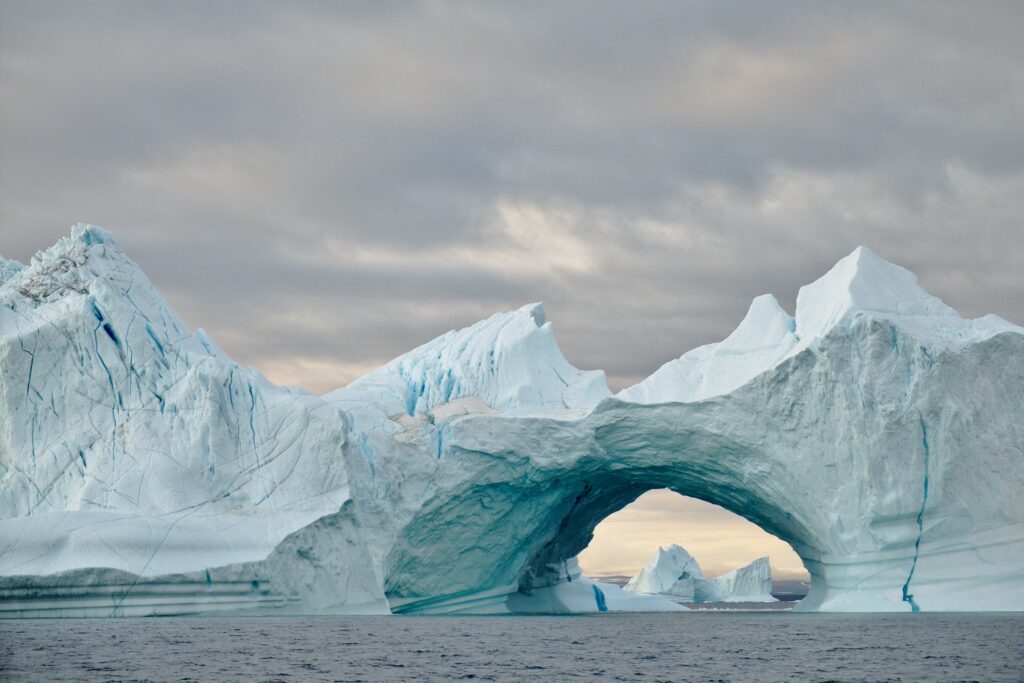 An icy structure forms an arch over the ocean.