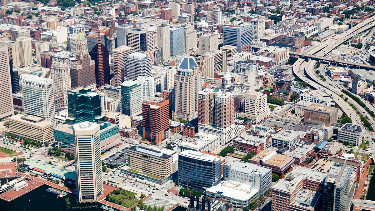 A city of pale buildings with a freeway running through it is seen from above.