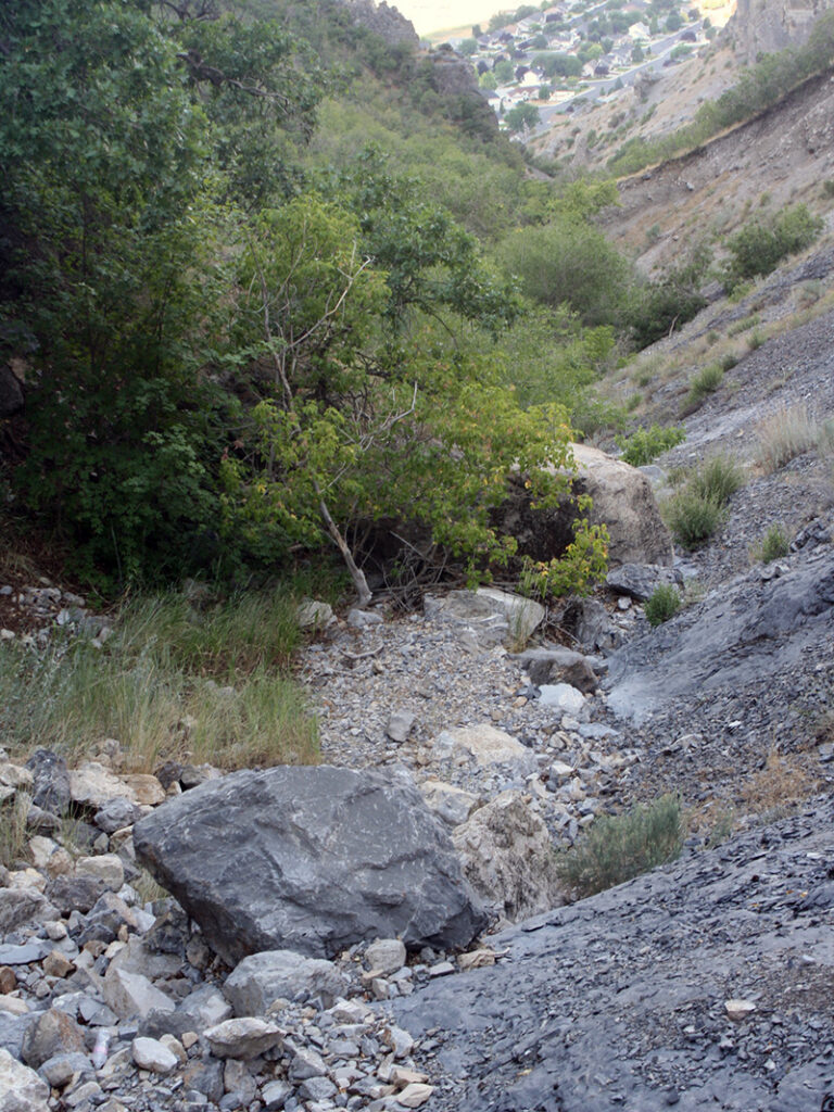 View looking down a dry, rocky ravine toward a neighborhood in the valley below.