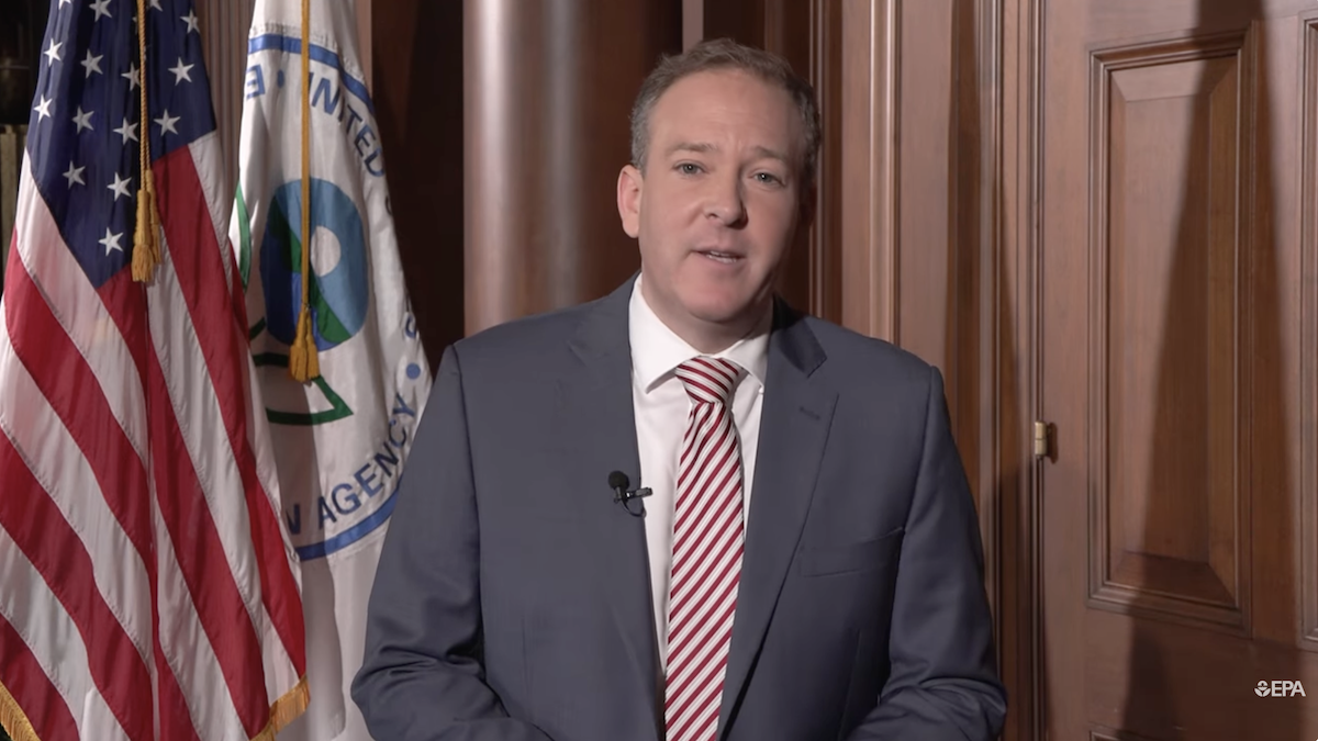 EPA Administrator Lee Zeldin, wearing a suit and tie, speaks to a camera with the United States flag and the EPA flag in the background.