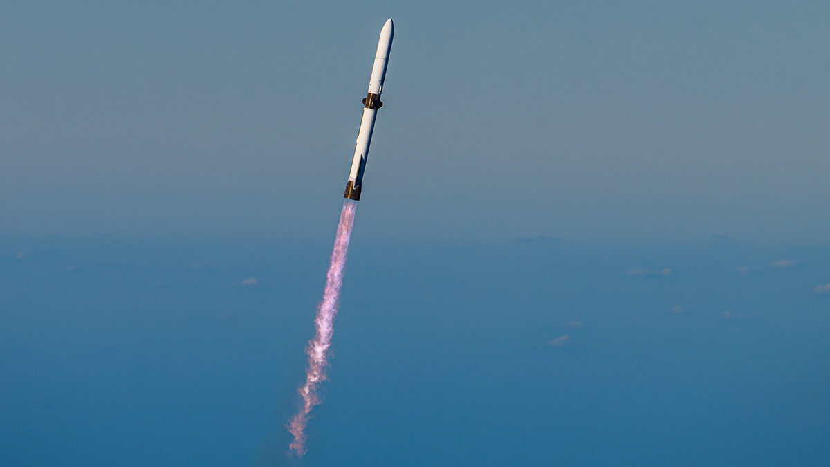 A rocket flies diagonally across a blue sky.