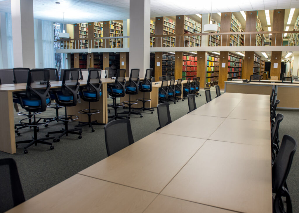 A well-lit library with two long worktables