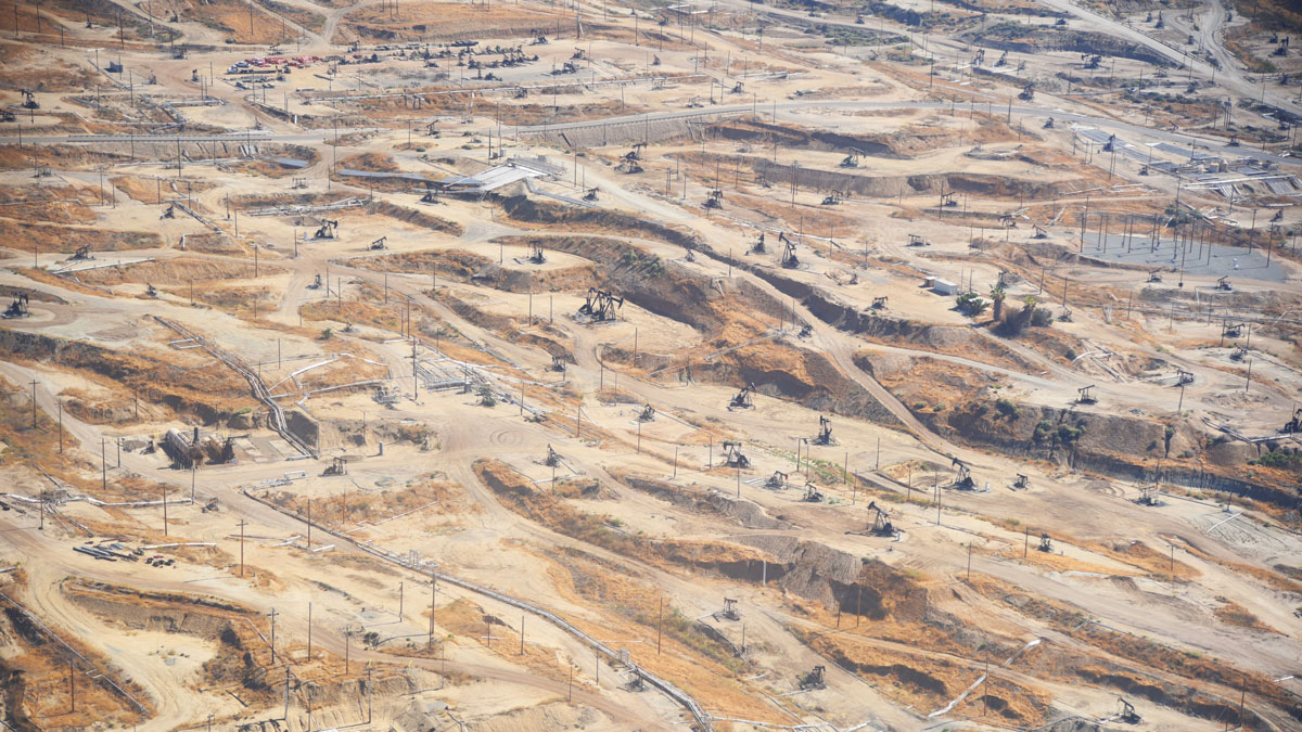 An overhead view of a desert dotted with roads, upright poles, and buildings.