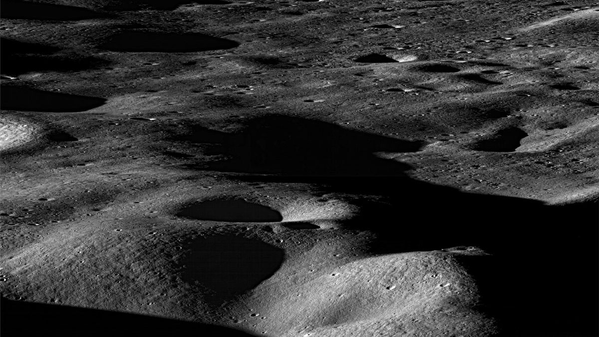 Dark gray mountains and craters, seen obliquely from above.