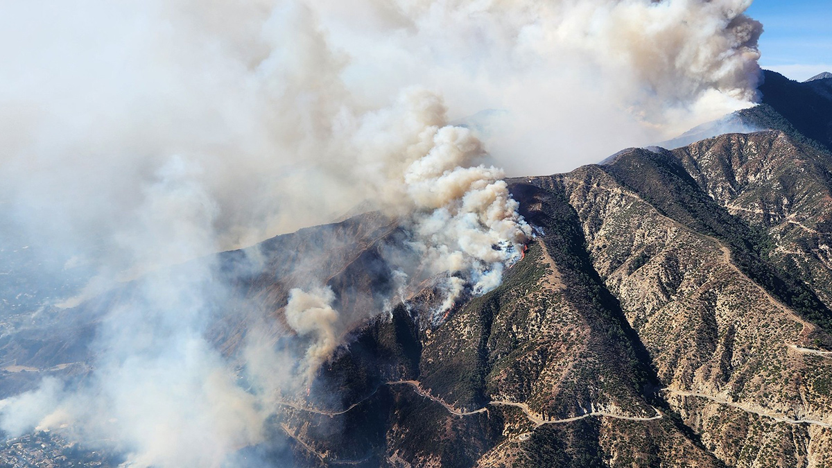 A plume of smoke rises from the side of a mountain.